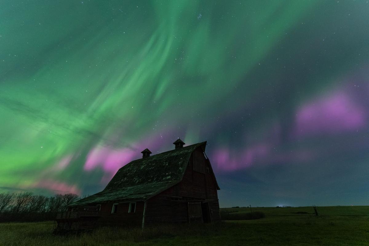 A bright pink and green aurora with a characterful Canadian barn in the foreground. (Courtesy of <a href="https://www.facebook.com/5elementsxposure">Gunjan Sinha</a>)