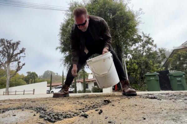 Former California Governor Arnold Schwarzenegger repairs a pothole on a street in his Los Angeles neighborhood on April 11, 2023. (The Office of Arnold Schwarzenegger via AP)