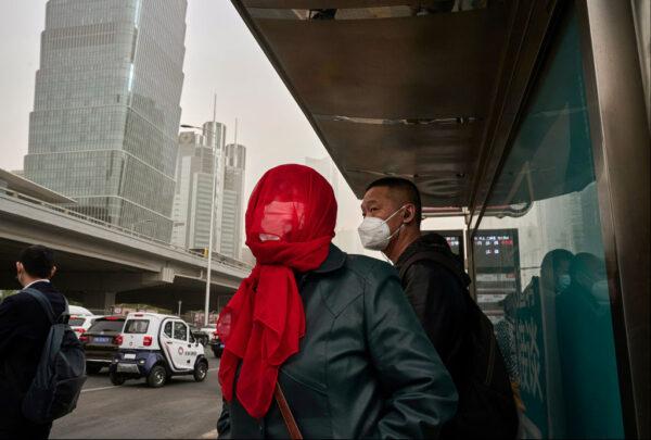 Commuters wait for a bus during a sandstorm in Beijing on April 11, 2023. (Kevin Frayer/Getty Images)