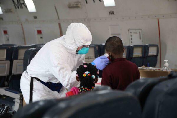 An operational medicine worker takes the temperature of a passenger boarding in Cameroon during the 2020 evacuation of U.S. citizens to the United States during the COVID-19 pandemic. (Photo courtesy of National Museum of American Diplomacy)