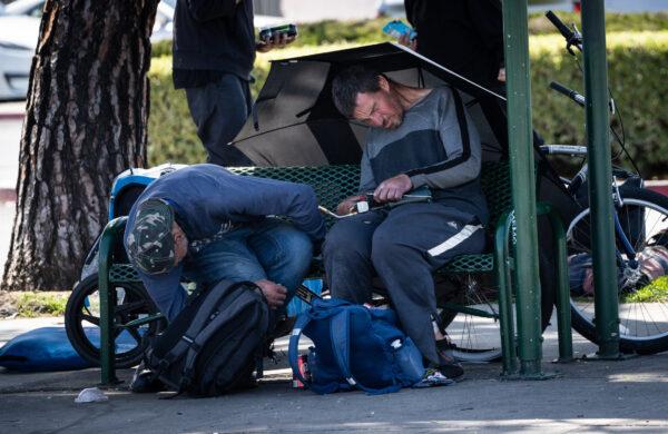 A homeless man uses a blowtorch to heat up his drugs in Garden Grove, Calif., on April 3, 2023. (John Fredricks/The Epoch Times)