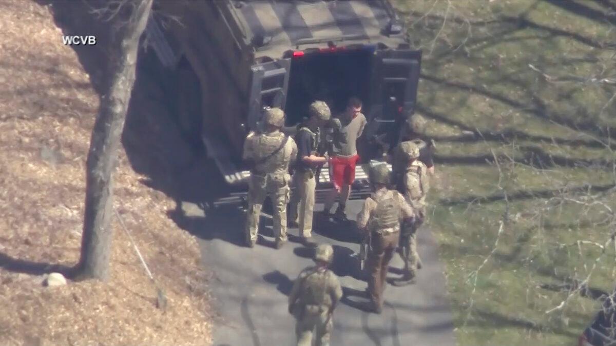 Jack Teixeira, in T-shirt and shorts, being taken into custody by armed tactical agents in Dighton, Mass., on April 13, 2023. (WCVB-TV via AP)