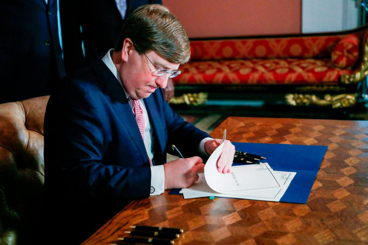 Mississippi Gov. Tate Reeves signs the bill retiring the last state flag with the Confederate battle emblem during a ceremony at the Governor's Mansion in Jackson, Miss., on June 30, 2020. (Rogelio V. Solis/AFP via Getty Images)