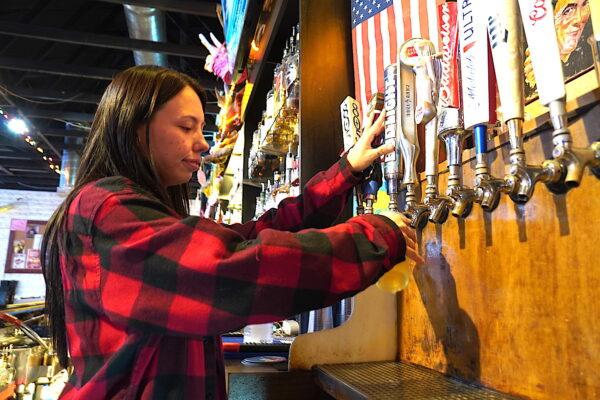 Sydney Encinas, a bartender at The Chaparral Bar in Cottonwood, Ariz., pours a glass of Budweiser Light on April 14, 2023. (Allan Stein/The Epoch Times)