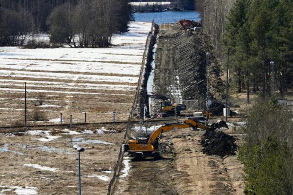 Excavators dig sand near a border fence with Russia in Pelkola, Finland, on April 14, 2023. (Janis Laizans/Reuters)