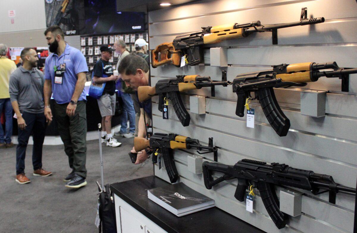 Members of the National Rifle Association walk past a rifle display during the group's Annual Meetings and Exhibits in Indianapolis, Ind., on April 15, 2023. (Michael Clements/The Epoch Times)