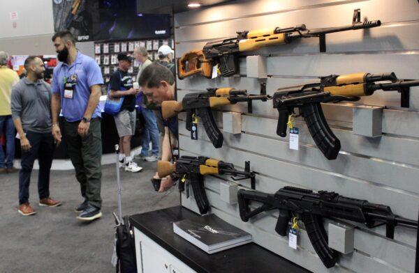 National Rifle Association members walk past a rifle display at the group's Annual Meetings and Exhibits in Indianapolis, Ind., on April 15, 2023. (Michael Clements/The Epoch Times)
