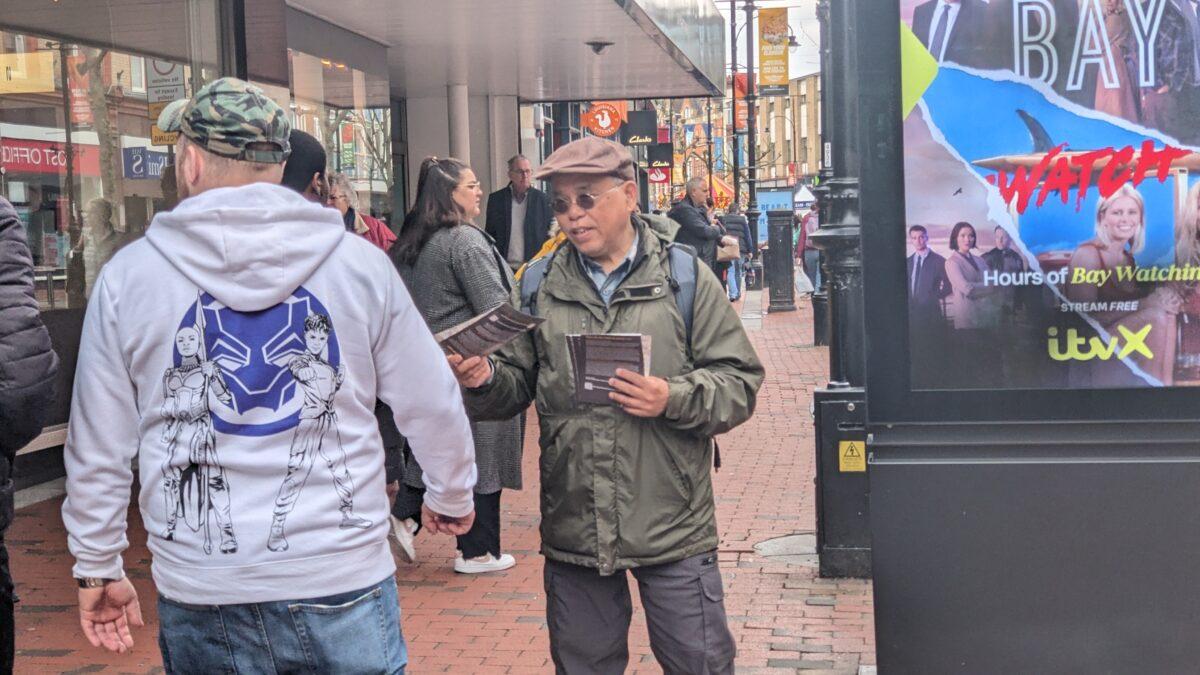Hong Kong scholar Chung Kim-wah arrived to volunteer for the event in Reading and distributed leaflets to passersby on April 15, 2023. (Shan Lam/The Epoch Times)