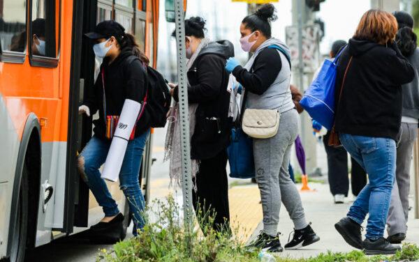 People board a bus wearing face masks amid the coronavirus pandemic in south Los Angeles, on April 6, 2020. (Mario Tama/Getty Images)