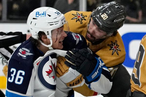 Vegas Golden Knights center Chandler Stephenson (20) helps Winnipeg Jets center Morgan Barron (36) after Barron cut his face on a skate during the first period of Game 1 of an NHL hockey Stanley Cup first-round playoff series in Las Vegas on April 18, 2023. (John Locher/AP Photo)