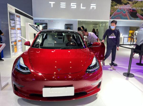 Visitors look at a Tesla Model 3 electric vehicle (EV ) at the third China International Consumer Products Expo in Haikou, Hainan province, China, on April 12, 2023. (Casey Hall/Reuters)