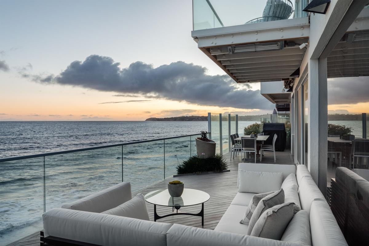 The living room spills out onto a deck overlooking the beach, and the bedrooms feature private glass-walled decks. (Courtesy of Stirling Reed and toptenrealestatedals.com)