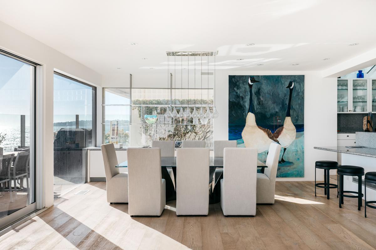 The dining room is conveniently adjacent to the kitchen and has dramatic hanging lighting, walls ideal for displaying large artwork, and clear views of the ocean. (Courtesy of Stirling Reed and toptenrealestatedals.com)
