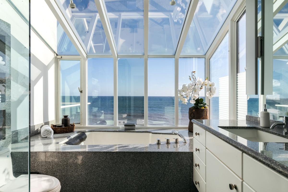 The master bath, with marble countertops, features an oversized tub and shower that provide a dramatic view of the beach and the ocean. (Courtesy of Stirling Reed and toptenrealestatedals.com)