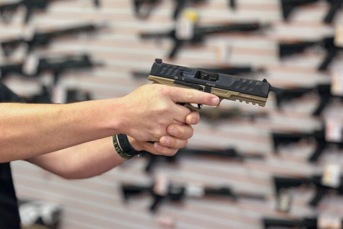 A gun salesman holds a Walther PDP Pro 9mm handgun at Lawful Defense in Gainesville, Fla., on April 19, 2023. (Nanette Holt/The Epoch Times)