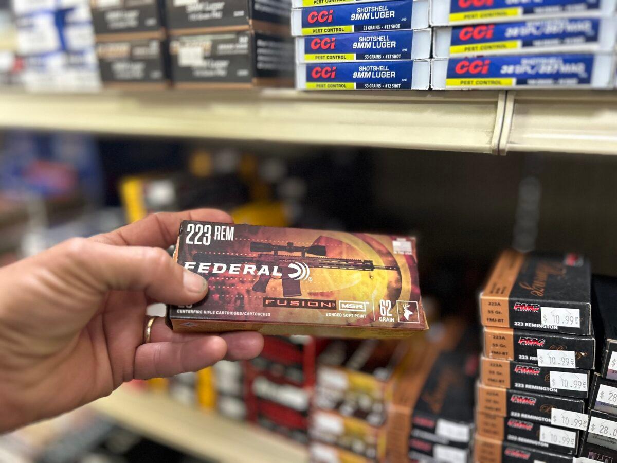 A customer pulls a box of .223 rounds for an AR-style rifle from a shelf full of ammunition at Lawful Defense in Gainesville, Fla., on April 19, 2023. (Nanette Holt/The Epoch Times)