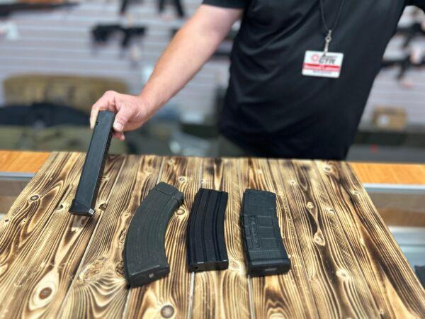 A gun store employee shows the differences between high-capacity magazines for a handgun (L), an AK-style rifle (2L), and AR-style rifles at Lawful Defense in Gainesville, Fla., on April 19, 2023. (Nanette Holt/The Epoch Times)