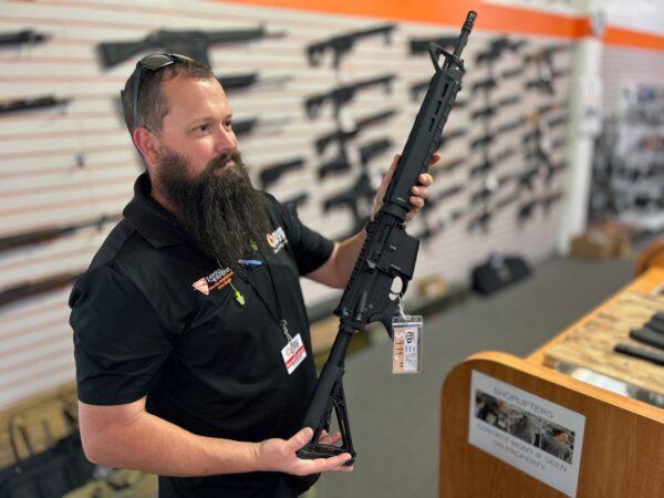 A gun store employee shows a customer an AR-style weapon at Lawful Defense in Gainesville, Fla., on April 19, 2023. AR stands for the ArmaLite rifle brand and the guns styled like it, and not "assault rifle," as commonly believed. (Nanette Holt/The Epoch Times)
