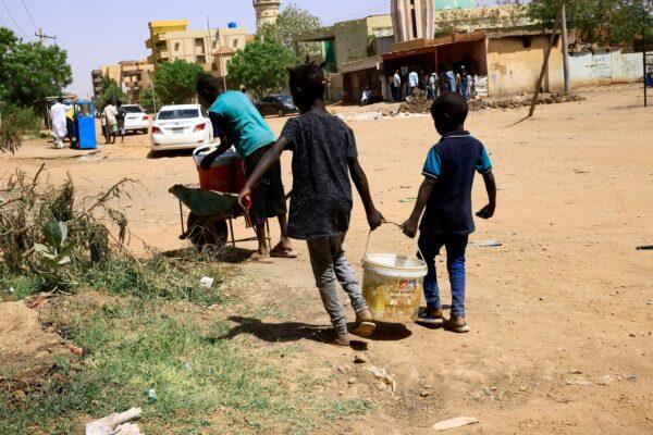 Children carry a bucket of water during clashes between the paramilitary Rapid Support Forces and the Sudanese army near Khartoum, Sudan, on April 22, 2023. (Mohamed Nureldin Abdallah/Reuters)