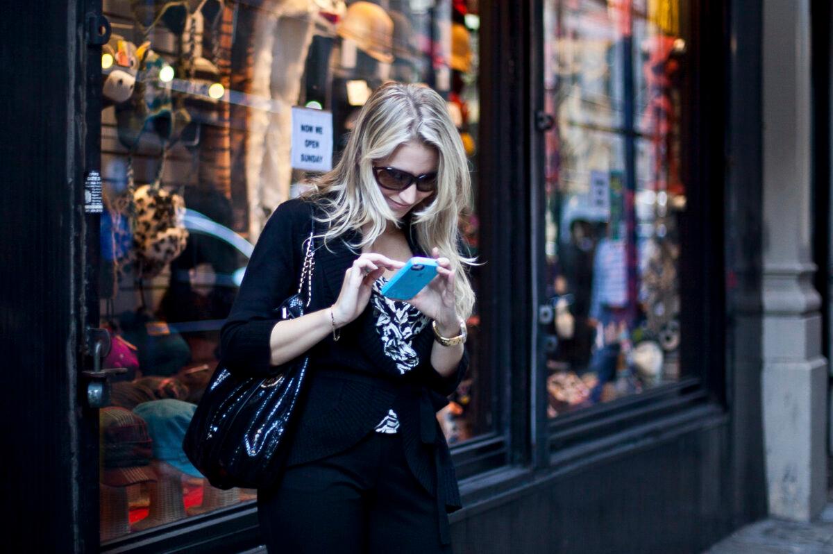 A woman checks her phone, in this file photo. (The Epoch Times)
