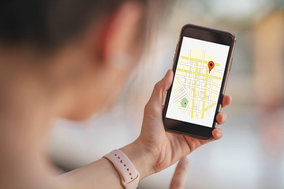 An illustration depicts a woman being located on a map on her smartphone. (Songsak C;  T.Whitney/Shutterstock)