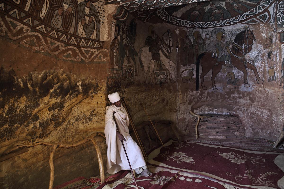 A monastic rests amid centuries-old paintings within the church Abuna Yemata Guh. (Vladimir Melnik/Shutterstock)