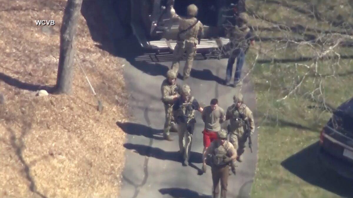 Jack Teixeira, in T-shirt and shorts, being taken into custody by armed tactical agents in Dighton, Mass., on April 13, 2023, (WCVB-TV via AP)