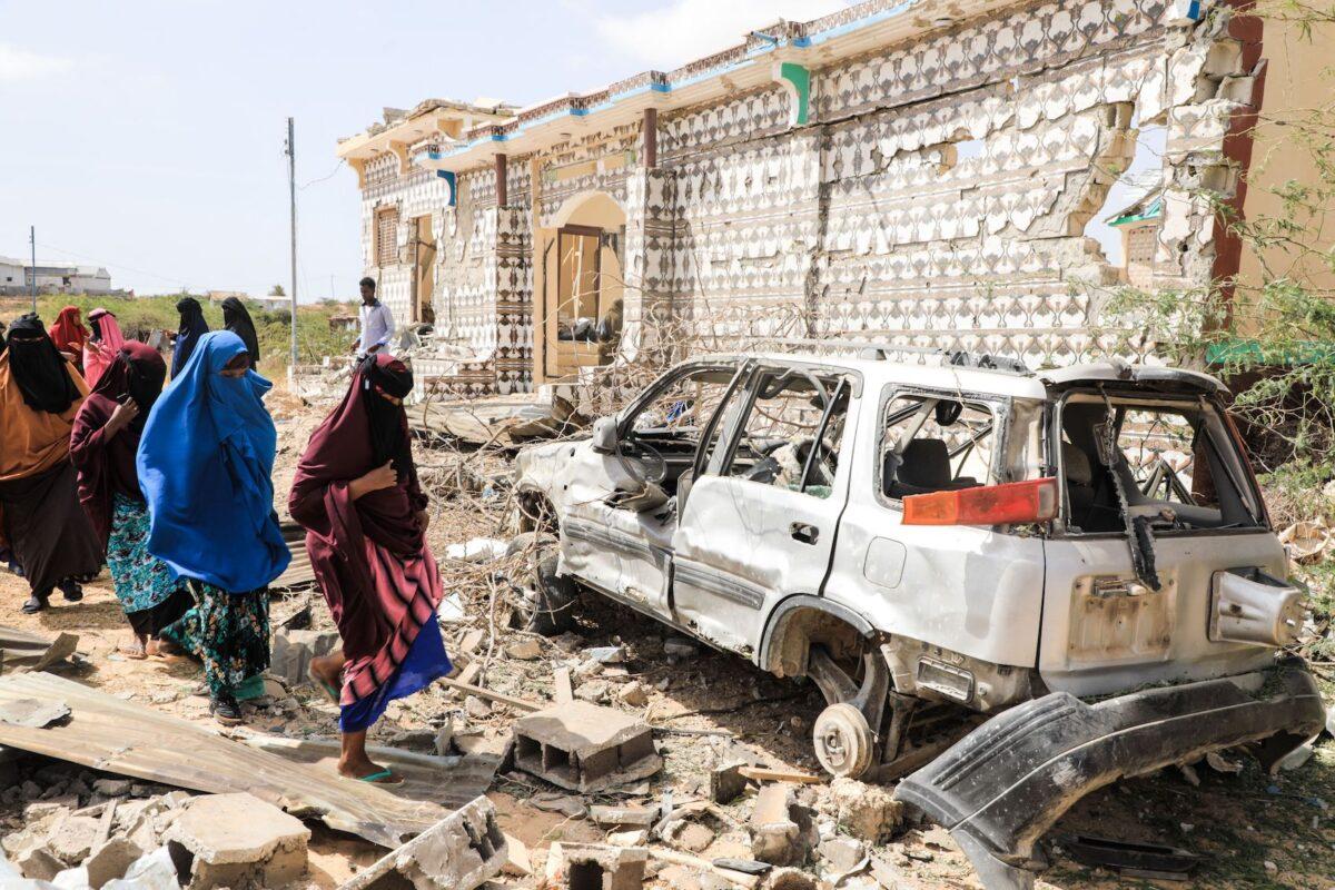 Women walk next to a destroyed house and the wreckage of a car following an explosion by al-Shabaab terrorists during an attack on a police station on the outskirts of Mogadishu, Somalia, on Feb. 16, 2022. (Hassan Ali Elmi/AFP via Getty Images)