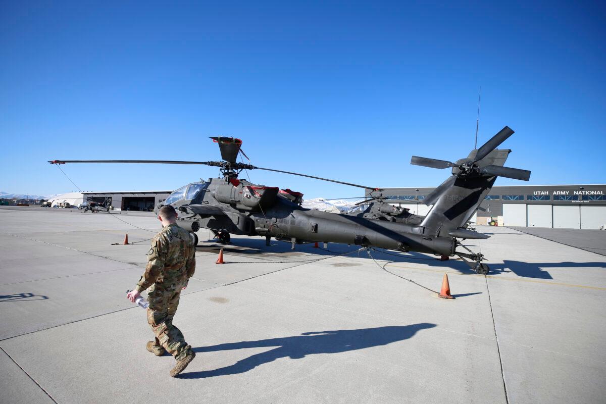 A maintenance worker walks past an AH-64 Apache helicopter in Kearns, Utah, on March 4, 2020. (George Frey/Getty Images)