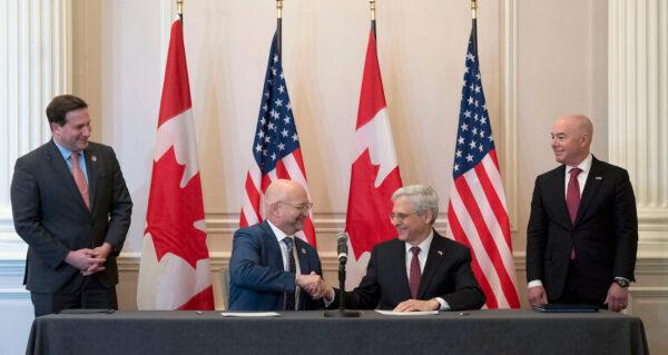 Public Safety Minister Marco Mendicino, left, and U.S. Secretary of Homeland Security Alejandro Mayorkas, right, look on as Minister of Justice and Attorney General of Canada David Lametti, center left, and U.S. Attorney General Merrick Garland shake hands after signing a document following the 2023 Canada–United States Cross-Border Crime Forum, in Ottawa, Ontario, on April 28, 2023. (Adrian Wyld/The Canadian Press via AP)