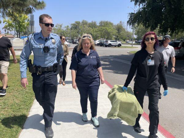 (L–R) Newport Beach Animal Control Officer Nick Ott, Executive Director of the Wetlands and Wildlife Care Center in Huntington Beach, Debbie McGuire, and Michelle Saldana, technician at the care center as they walk the Mallard duck to its release spot at TeWinkle park in Costa Mesa, Calif., on April 28, 2023. (Carol Cassis/The Epoch Times)