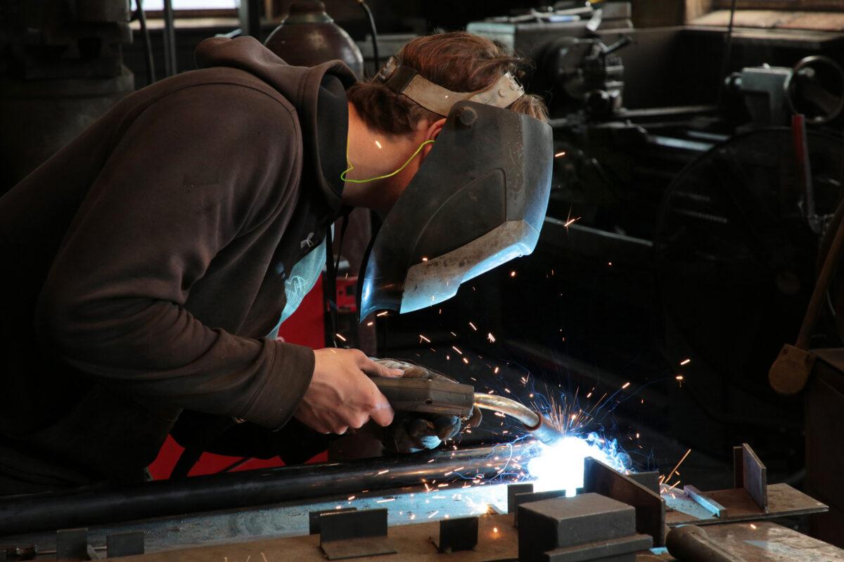 A young Amish man uses an arc welder in a metal workshop in Ronks, Pa., on April 26, 2023. (Richard Moore/The Epoch Times)