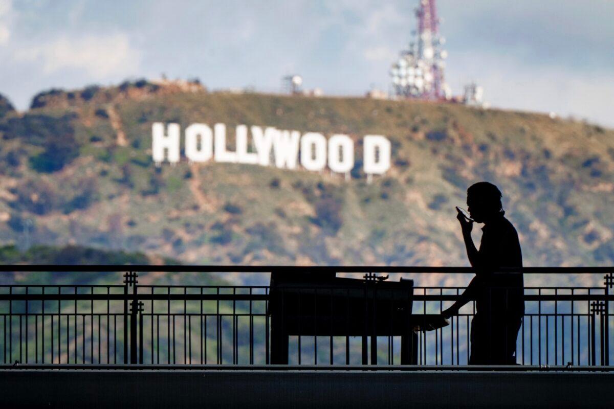 A worker wheels equipment past the famous Hollywood sign as preparations continue for the 95th Academy Awards at the Dolby Theatre in Los Angeles on March 8, 2023. (J. David Ake/AP Photo)