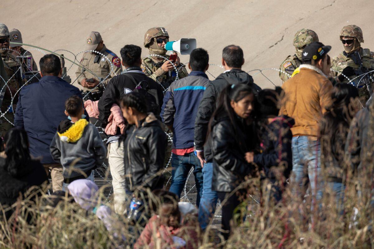 A Texas National Guard soldier speaks to illegal immigrants at a high-traffic illegal border crossing area along Rio Grande in El Paso, Texas, on Dec. 20, 2022. (John Moore/Getty Images)