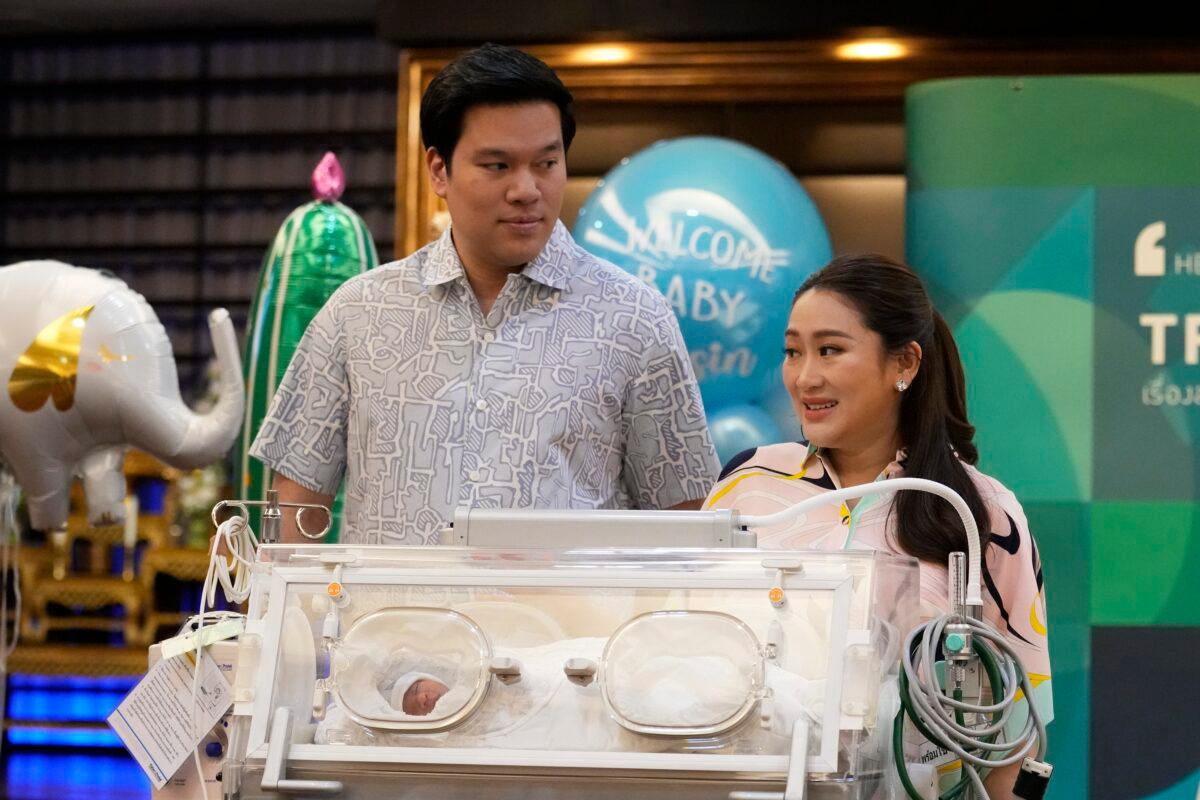 Paetongtarn Shinawatra (R), a leading Thai politician and youngest daughter of exiled former deposed Thai leader Thaksin Shinawatra, stands behind an incubator with her new born son, along with (L) her husband Pidok Sooksawas during press conference in Bangkok on May 3, 2023. (Sakchai Lalit/AP Photo)