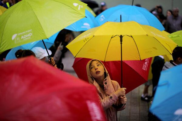 Young children dance with their umbrellas at the launch of an art installation called the Umbrella Project to raise awareness of ADHD and autism in children, featuring 200 brightly coloured umbrellas suspended over Church Alley in Liverpool, England, on June 22, 2017. (Christopher Furlong/Getty Images)