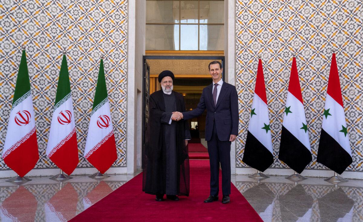 Syrian President Bashar al-Assad stands with Iranian President Ebrahim Raisi in Damascus, Syria, in this handout released by SANA, on May 3, 2023. (Sana/Reuters)