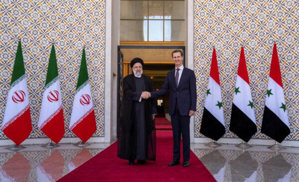 Syrian President Bashar al-Assad stands with Iranian President Ebrahim Raisi in Damascus, Syria, in this photo released by Syrian Arab News Agency on May 3, 2023. (SANA/Handout via REUTERS)