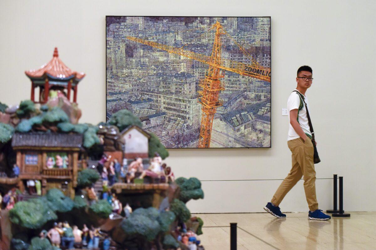 A man walks past artworks by the Sichuan Fine Arts Institute at China's National Art Museum, in Beijing on June 15, 2017. (Wang Zhao/AFP via Getty Images)