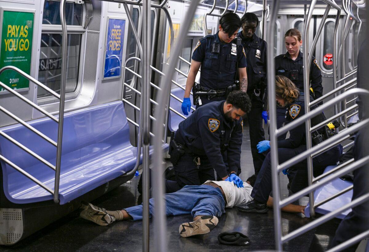 New York police officers administer CPR to a man at the scene where a fight was reported on a subway train in New York on May 1, 2023. (Paul Martinka via AP)