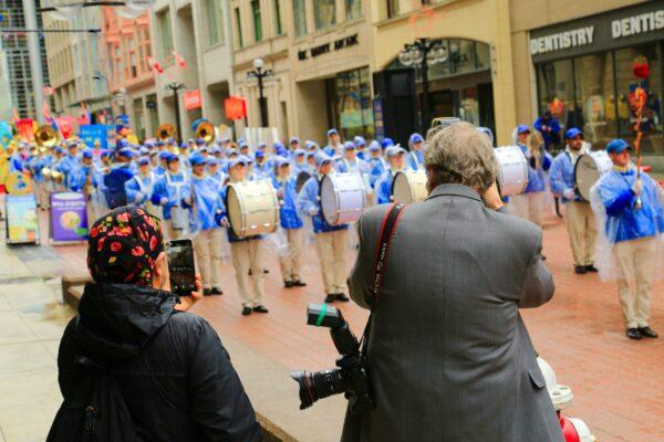 People take photos of the Tianguo Marching Band as it performs in Ottawa on May 3, 2023, to celebrate Falun Dafa Day. (Jonathan Ren/The Epoch Times)