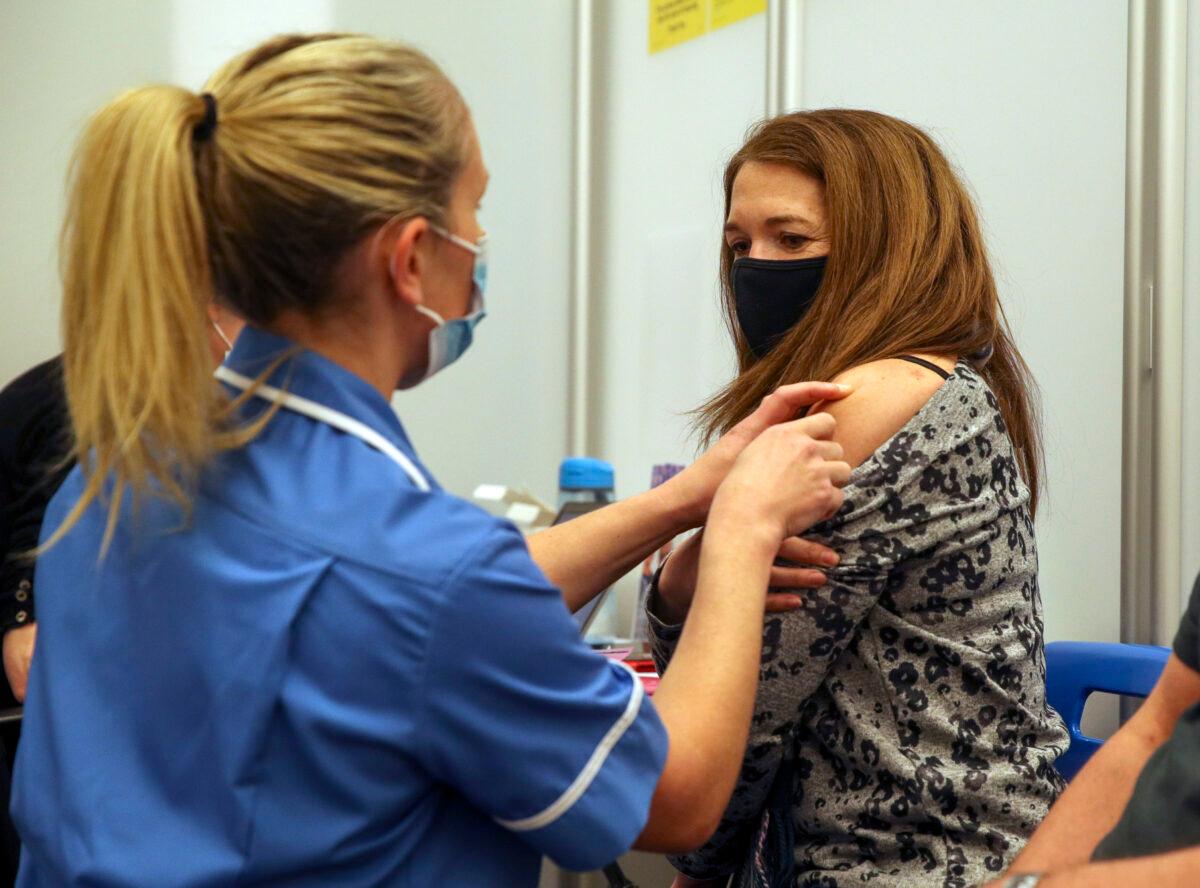Caroline Nicolls receives an injection of the Moderna COVID-19 vaccine administered by nurse Amy Nash, at the Madejski Stadium in Reading, England, on April 13, 2021. (Steve Parsons - WPA Pool/Getty Images)