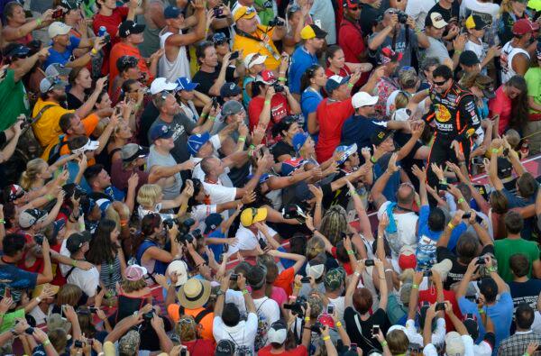 Tony Stewart (R) slaps hands with fans while walking down the runway during driver introductions prior to the NASCAR Sprint Cup auto race at Daytona International Speedway in Daytona Beach, Fla., on July 6, 2013. (Phelan M. Ebenhack/AP Photo)
