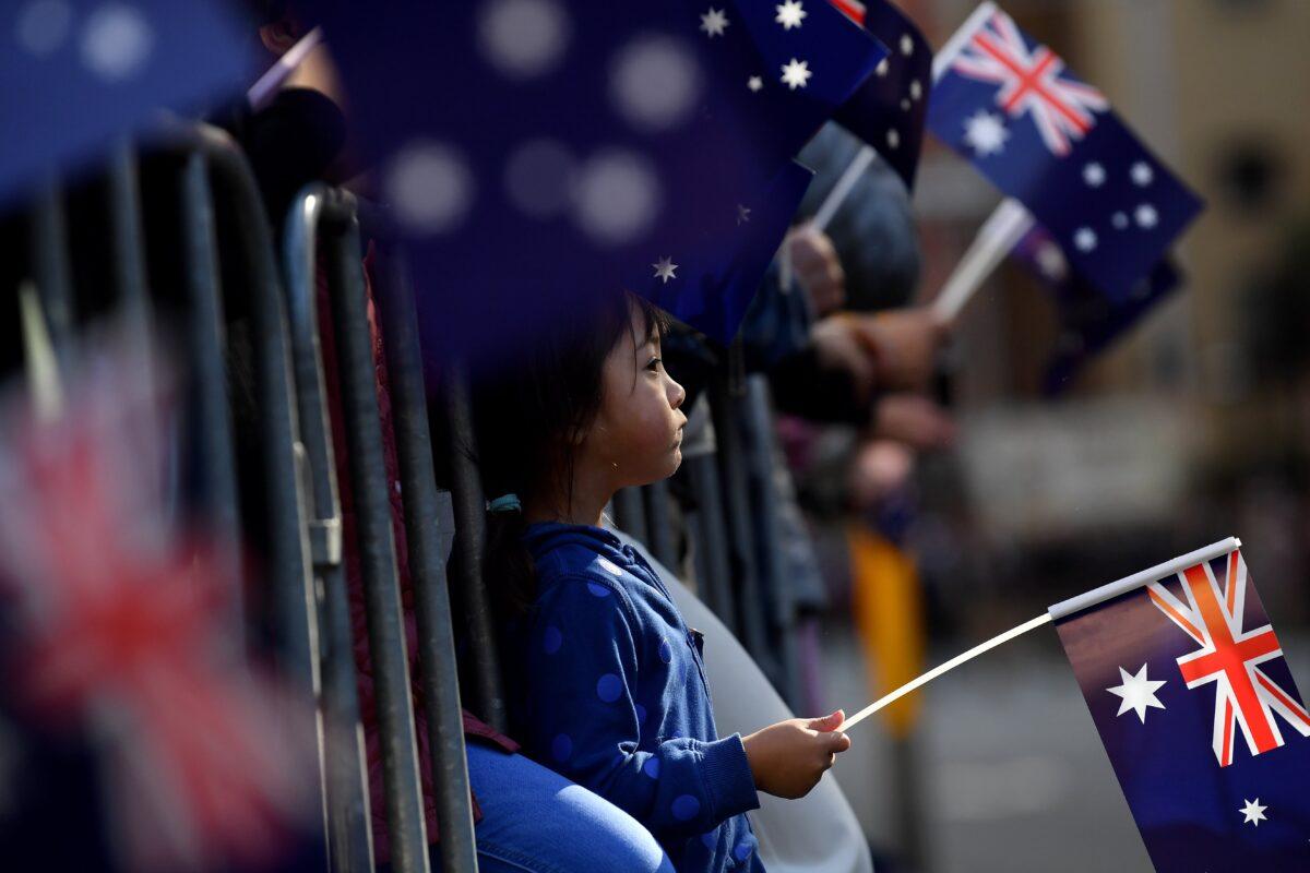 Members of the public wave the Australian flag as they watch the Anzac Day March in Sydney, Australia, on April 25, 2023. (AAP Image/Bianca De Marchi)