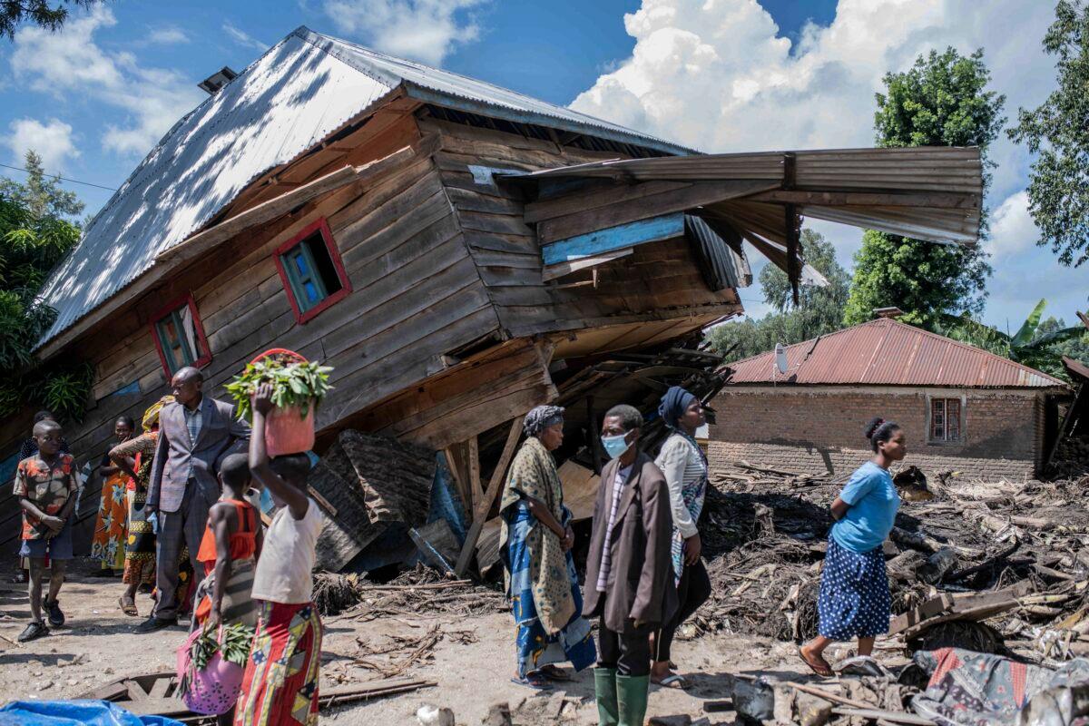 People walk next to a house destroyed by the floods in the village of Nyamukubi, South Kivu province in Congo on May 6, 2023. (Moses Sawasawa/AP Photo)