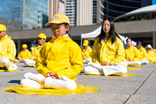 Falun Dafa adherents demonstrate the practice's meditation during a rally at Toronto City Hall on May 6, 2023. (Evan Ning/The Epoch Times)