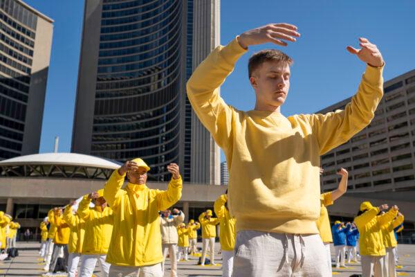Falun Gong practitioners demonstrate meditative exercises during a rally at Toronto City Hall on May 6, 2023. Hundreds of people attended the event to mark the 31st anniversary of the public introduction of the spiritual practice Falun Dafa. (Evan Ning/The Epoch Times)