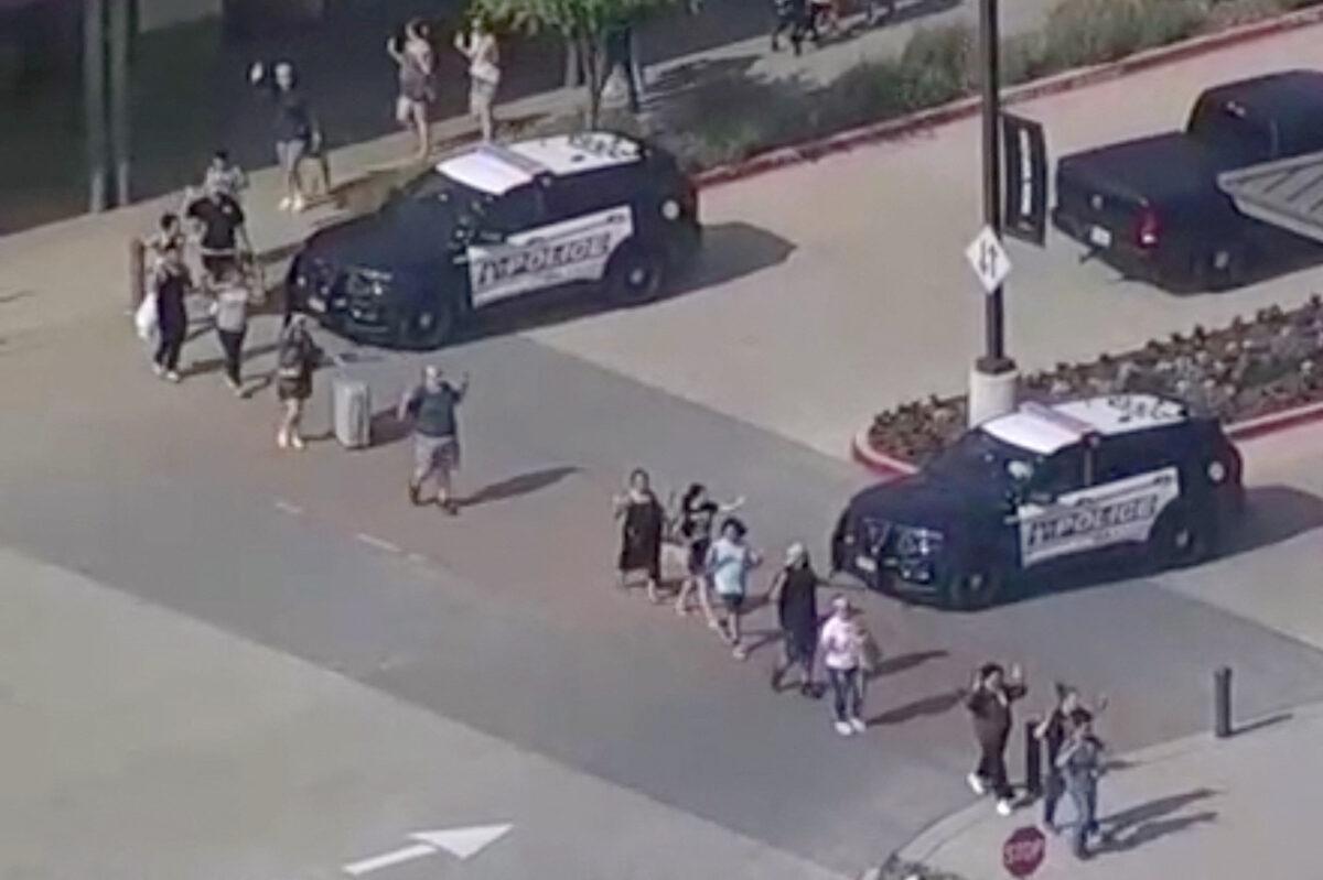 A still image from video shows shoppers leave with hands up as police respond to a shooting in the Dallas area's Allen Premium Outlets, in Allen, Texas, on May 6, 2023. (WFAA TV via Reuters)