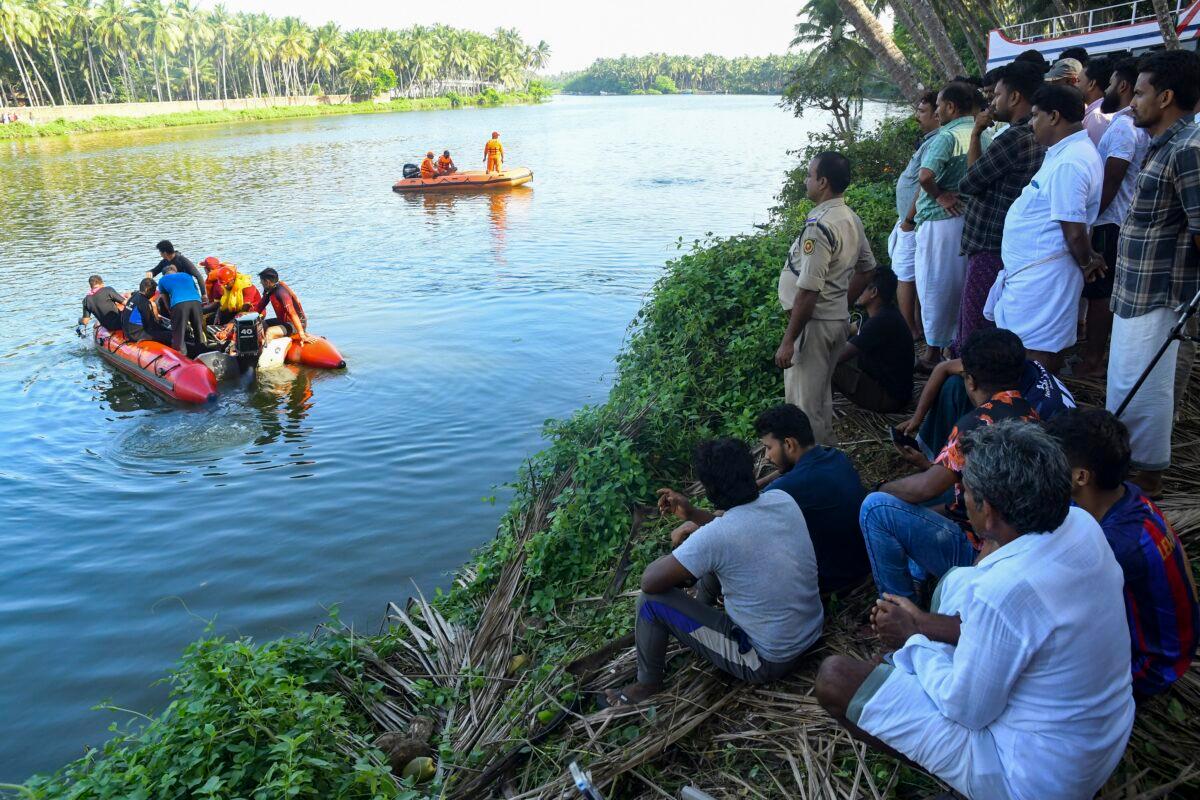 People watch rescuers on a boat search a river after a tourist boat capsized Sunday night in Malappuram, Kerala, India, on May 8, 2023. (P.P. Afthab/AP Photo)