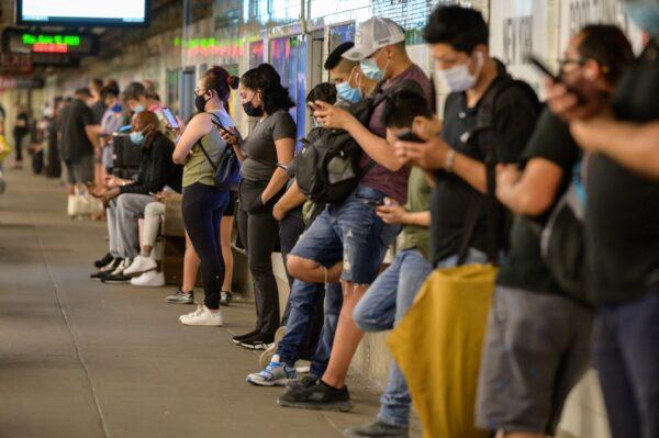 Commuters looks at their mobile phones as they wait for a subway train in New York on June 10, 2021. (ED JONES/AFP via Getty Images)